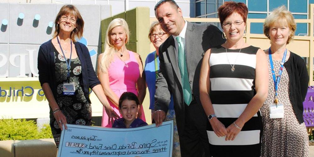 Upstate employees and patient with donated check for spina bifida